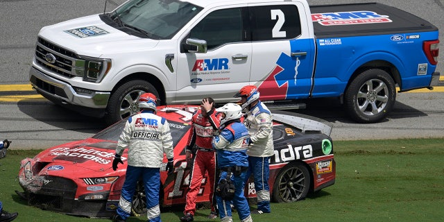 Chase Briscoe (14) is helped away from his car after wrecking along the front stretch after coming out of Turn 4 during a NASCAR Cup Series auto race at Daytona International Speedway, Sunday, Aug. 28, 2022, in Daytona Beach, Fla.