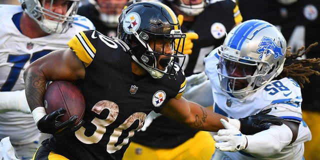 Jaylen Warren, #30 of the Pittsburgh Steelers, carries the ball in front of James Houston, #59 of the Detroit Lions, during the fourth quarter at Acrisure Stadium on Aug. 28, 2022, in Pittsburgh.