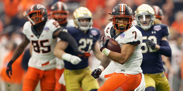 Running back Jaylen Warren, #7 of the Oklahoma State Cowboys, carries the football against the Notre Dame Fighting Irish during the PlayStation Fiesta Bowl at State Farm Stadium on Jan. 1, 2022, in Glendale, Arizona.