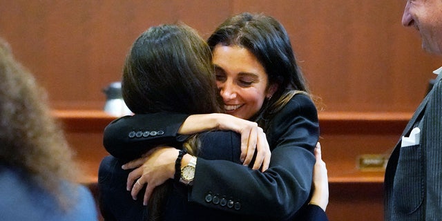 Attorney Joelle Rich hugs attorney Camille Vasquez, back to camera, as attorney Ben Chew looks on at the end of the daily proceedings at the Fairfax County Circuit Courthouse in Fairfax, Virginia, on May 16, 2022.