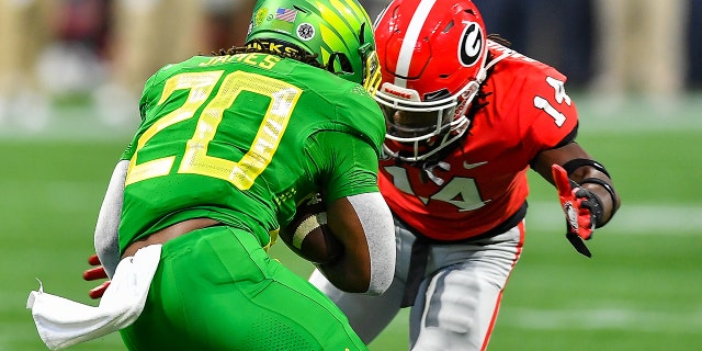 Oregon running back Jordan James, #20, is tackled by Georgia defensive back David Daniel-Sisavanh, #14, during the Chick-Fil-A Kickoff Game between the Oregon Ducks and the Georgia Bulldogs on Sept. 3, 2022 at Mercedes-Benz Stadium in Atlanta.