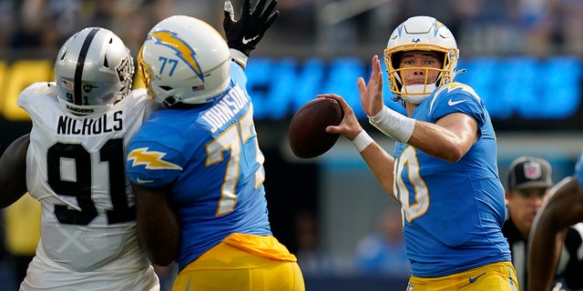 Los Angeles Chargers quarterback Justin Herbert, right, passes as Las Vegas Raiders defensive tackle Bilal Nichols, #91, applies pressure during the second half of an NFL football game in Inglewood, California, Sunday, Sept. 11, 2022.