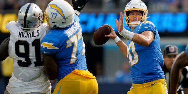 Los Angeles Chargers quarterback Justin Herbert, right, passes as Las Vegas Raiders defensive tackle Bilal Nichols, #91, applies pressure during the second half of an NFL football game in Inglewood, California, Sunday, Sept. 11, 2022.