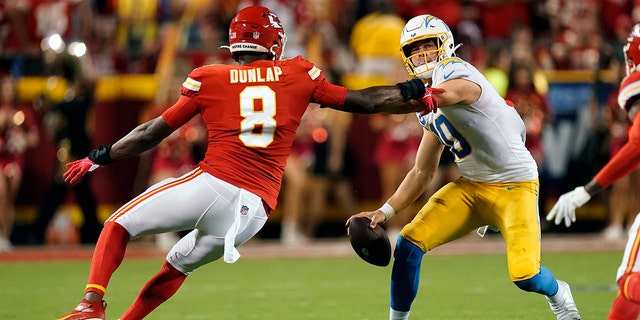 Los Angeles Chargers quarterback Justin Herbert, right, scrambles as Kansas City Chiefs defensive end Carlos Dunlap II (8) defends during the first half of an NFL football game Thursday, Sept. 15, 2022, in Kansas City, Mo.