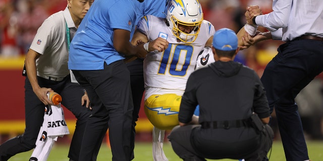 Justin Herbert #10 of the Los Angeles Chargers was rescued from the field by medical staff following an injury during the fourth quarter of a game against the Kansas City Chiefs at Arrowhead Stadium in Kansas City, Missouri, on Sept. 15, 2022.