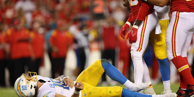 Justin Herbert #10 of the Los Angeles Chargers lays on the ground after being hit during the fourth quarter against the Kansas City Chiefs at Arrowhead Stadium on September 15, 2022 in Kansas City, Missouri.