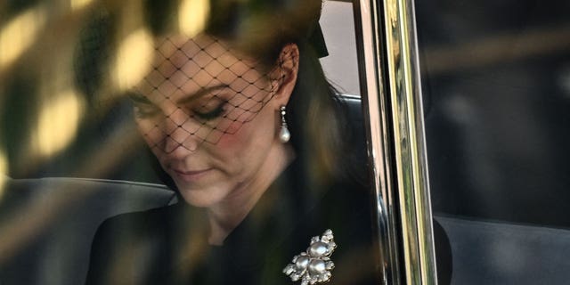 Kate Middleton wearing the queen's brooch as she pays her respects.