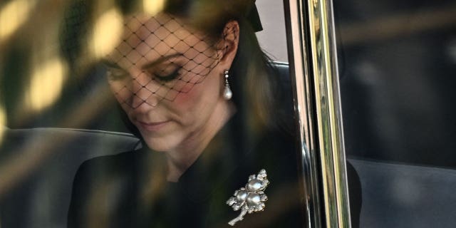 Kate Middleton wearing the queen's brooch as she pays her respects.