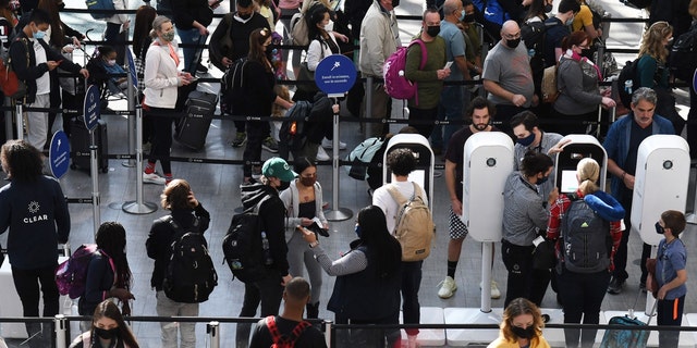 Se ve a personas en una línea de control de seguridad de la TSA en el Aeropuerto Internacional de Orlando dos días antes de Navidad en 2021.