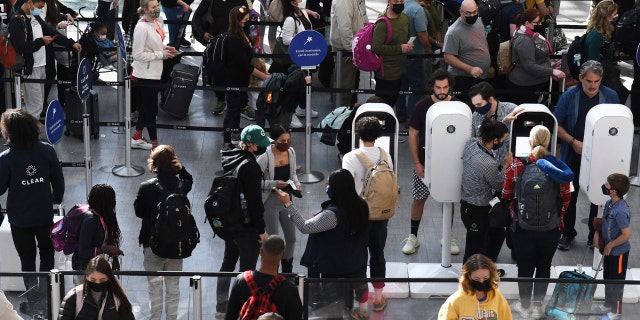 People are seen in a TSA security checkpoint line at Orlando International Airport two days before Christmas in 2021.