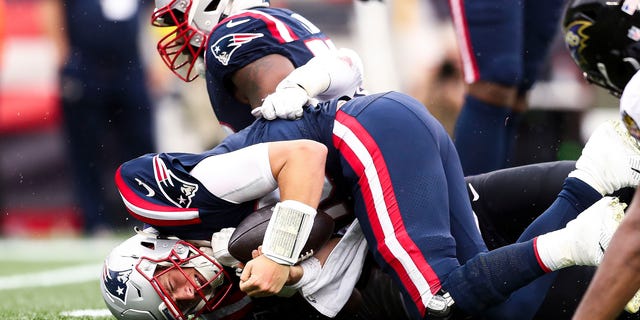 Quarterback Mac Jones of the New England Patriots, foreground, reacts after being sacked during the fourth quarter against the Baltimore Ravens at Gillette Stadium Sept. 25, 2022, in Foxborough, Mass.