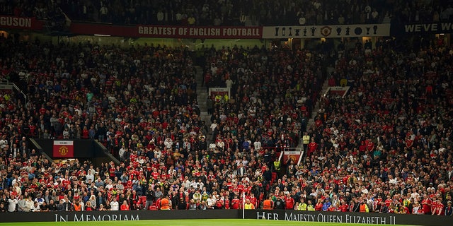 Manchester United fans observe a minutes silence following the death of Queen Elizabeth II, ahead of the group E Europa League soccer match between Manchester United and Real Sociedad at Old Trafford in Manchester, England, Thursday, Sept. 8, 2022.