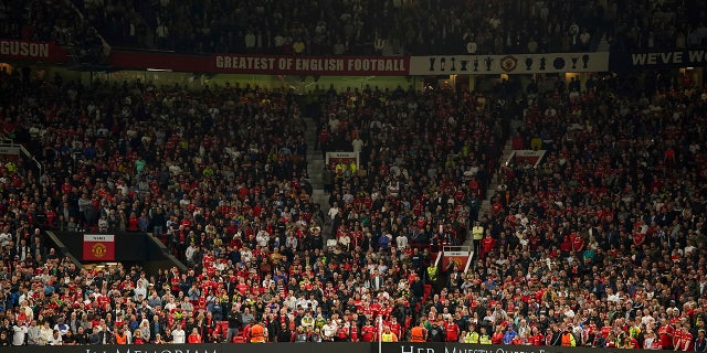 Manchester United fans observe a minutes silence following the death of Queen Elizabeth II, ahead of the group E Europa League soccer match between Manchester United and Real Sociedad at Old Trafford in Manchester, England, Thursday, Sept. 8, 2022.