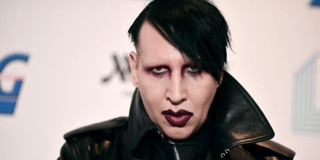 Marilyn Manson walks red carpet wearing black leather jacket and lipstick