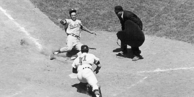 Maury Wills of the Los Angeles Dodgers slides home safely past John Romano of the Cleveland Indians during the eighth inning of the All-Star Game in Washington on July 10, 1962.