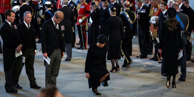 Meghan Markle curtsying as she pays her respects to Queen Elizabeth II.