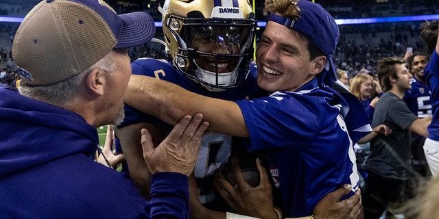 Fans celebrate with Washington quarterback Michael Penix Jr., center, after a victory over Michigan State on Sept. 17, 2022, in Seattle.