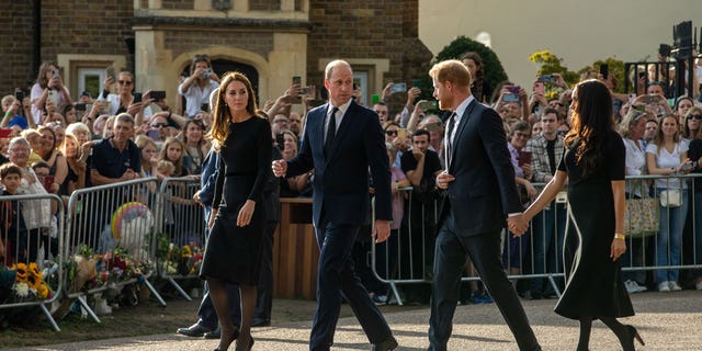 Kate Middleton and Prince William walk alongside Prince Harry and Meghan Markle, who are holding hands after Queen Elizabeth II's death. 