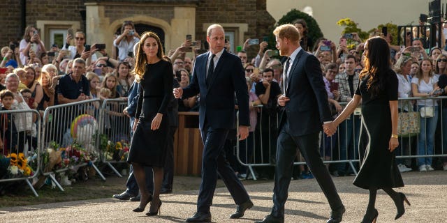 Kate Middleton and Prince William walk alongside Prince Harry and Meghan Markle, who are holding hands after Queen Elizabeth II's death. 