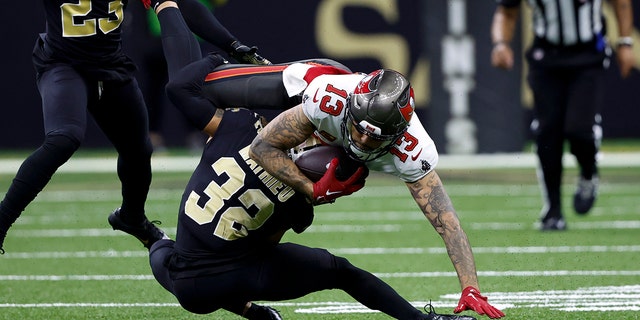 Tampa Bay Buccaneers wide receiver Mike Evans is tackled by New Orleans Saints safety Tyrann Mathieu during the first half in New Orleans on Sept. 18, 2022.