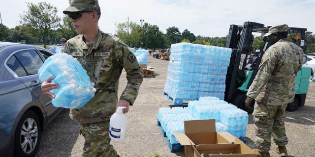 Mississippi National Guardsmen carry cases of drinking water and a bottle of hand sanitizer to Jackson, Miss., residents, Friday, Sept. 2, 2022, at Smith Wills Stadium. Jackson's water system partially failed following flooding and heavy rainfall that exacerbated longstanding problems in one of two water-treatment plants, and the state is helping with the distribution of drinking water to the city's residents. 