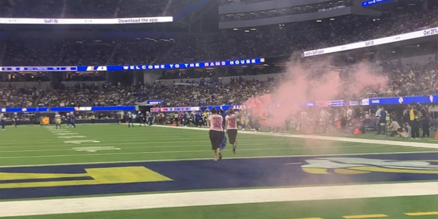 Two women rush SoFi Stadium field with smoke flares to highlight upcoming trial.