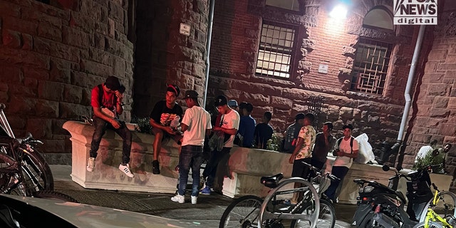 A group of people, said to be newly arrived migrants, congregate outside a packed New York City homeless shelter. 