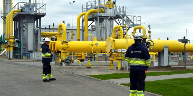 FILE: Workers stand near the pipelines during an opening ceremony of the Baltic Pipe in Budno, Poland, Tuesday, Sept. 27, 2022.