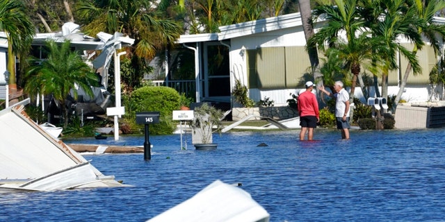 Trailer park residents talk in a flooded area after Hurricane Ian passed by Thursday, Sept. 29, 2022, in Fort Myers, Fla. 