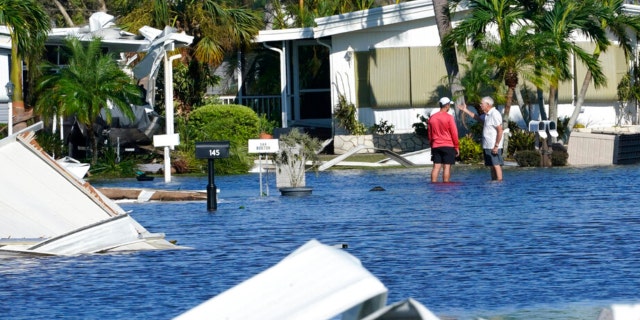 Trailer park residents talk in a flooded area after Hurricane Ian passed by Thursday, Sept. 29, 2022, in Fort Myers, Fla.