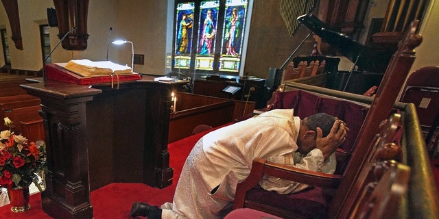 Rev. Dr. Gregory G. Groover, Sr., pastor of The Historic Charles Street A.M.E. Church in Roxbury, prays at the church in Boston on April 10, 2020.