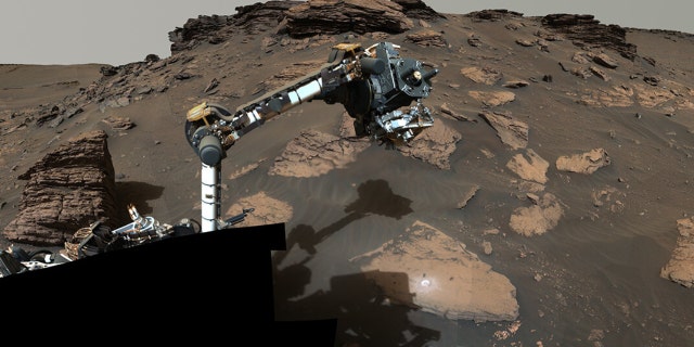 Der Rover der NASA legt seinen Roboterarm um einen Felsvorsprung namens "Skinner Ridge" Im Marskrater Jezero. Dieses Mosaik besteht aus mehreren Bildern und zeigt geschichtete Sedimentgesteine, die einer Klippe im Delta zugewandt sind, sowie eine der Stellen, an denen der Rover einen kreisförmigen Fleck abgekratzt hat, um die Felsformation zu analysieren.
