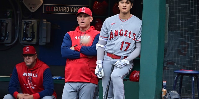 El mánager interino de los Angelinos de Los Ángeles, Phil Nevin, a la izquierda, y Shohei Ohtani parados en el banquillo durante la primera entrada del partido de béisbol del equipo contra los Guardianes de Cleveland, el martes 13 de septiembre de 2022, en Cleveland. 