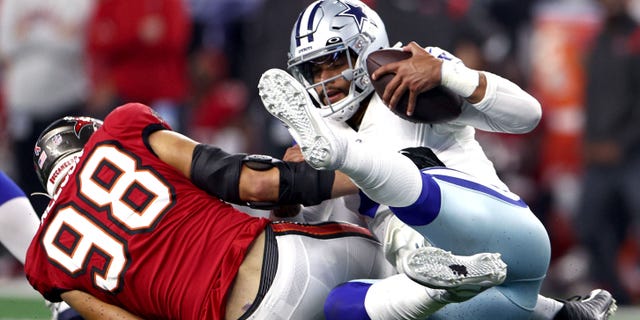 Anthony Nelson # 98 des Buccaneers de Tampa Bay limoge Dak Prescott # 4 des Cowboys de Dallas au cours de la seconde mi-temps le 11 septembre 2022 à Arlington, Texas.