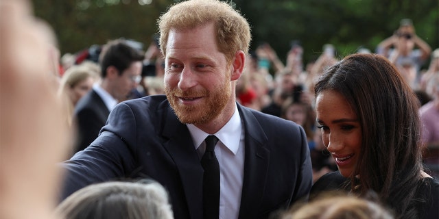 Britain's Prince Harry and Meghan, Duchess of Sussex greet people walking outside Windsor Castle after the death of Queen Elizabeth of England on September 10, 2022 in Windsor, England. 