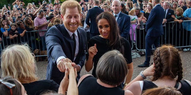 El príncipe Harry y Meghan saludan a los simpatizantes fuera del castillo de Windsor.