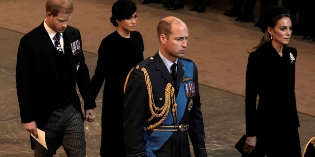 Prince William and Kate Middleton lead procession as Queen Elizabeth II's coffin is transported to Westminster Hall, with Prince Harry and Meghan Markle standing in the distance.