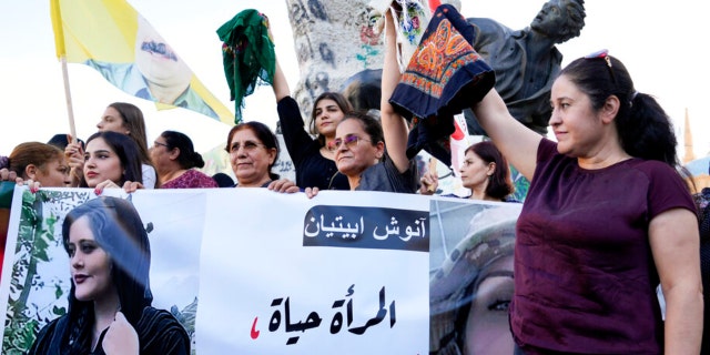 Kurdish women activists hold headscarves and a portrait of Iranian woman Mahsa Amini, with Arabic that reads, "The woman is life, don't kill the life," during a protest against her death in Iran, at Martyrs' Square in downtown Beirut, Sept. 21, 2022.