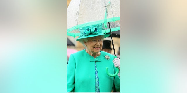 Queen Elizabeth II shelters from the rain under an umbrella as she hosts a garden party at Buckingham Palace on July 19, 2011 in London, England.