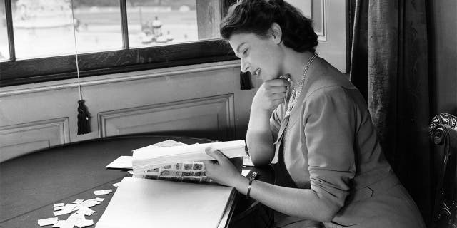 Princess Elizabeth looking through her stamp collection in the State Apartments at Buckingham Palace in July 1946.