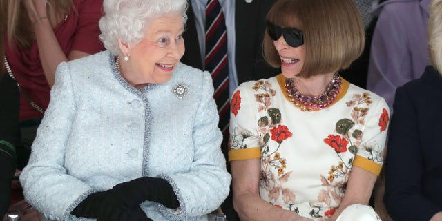 Queen Elizabeth II sits next to Anna Wintour as they view Richard Quinn's runway show before presenting him with the inaugural Queen Elizabeth II Award for British Design.