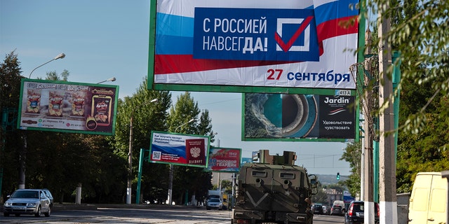 Bir askeri araç, bir reklam panosu okuma ile bir cadde boyunca ilerliyor "Sonsuza kadar Rusya ile, 27 Eylül" Luhansk'taki referandum öncesinde, Rusya destekli ayrılıkçılar tarafından kontrol edilen Luhansk Halk Cumhuriyeti, doğu Ukrayna, 22 Eylül 2022 Perşembe.