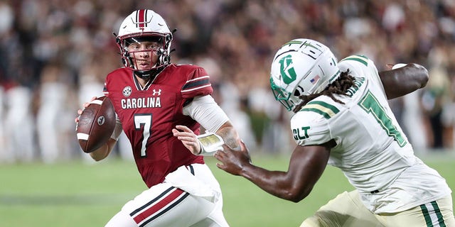 South Carolina quarterback Spencer Rattler (7) scrambles away from Charlotte defensive lineman Amir Siddiq (1) during the first half of an NCAA college football game on Saturday, Sept. 24, 2022, in Columbia, S.C.