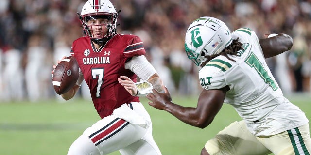 South Carolina quarterback Spencer Rattler (7) scrambles away from Charlotte defensive lineman Amir Siddiq (1) during the first half of an NCAA college football game on Saturday, Sept. 24, 2022, in Columbia, S.C.