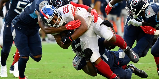 New York Giants running back Saquon Barkley (26) is stopped by the Tennessee Titans defense during the second half of an NFL football game Sunday, Sept. 11, 2022, in Nashville.