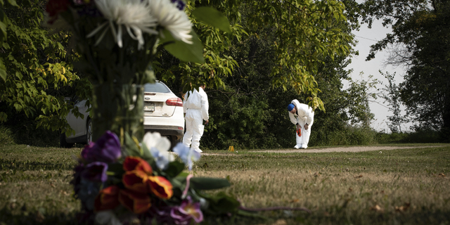 Investigators examine the crime scene near a memorial of flowers outside the home of Wes Petterson in Weldon, Saskatchewan, on Monday, Sept. 5.