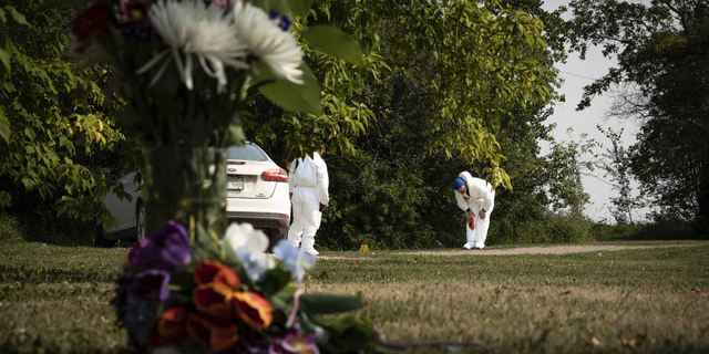 Investigators examine the crime scene near a memorial of flowers outside the home of Wes Petterson in Weldon, Saskatchewan, on Monday, Sept. 5.