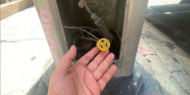 New York City utility poles have a panel at the bottom containing ordinary household light sockets. A homeless man recently slept next to this West 43rd Street utility pole in Midtown Manhattan, with a toaster oven in tow.