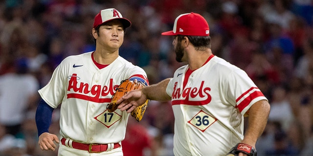 Los Angeles Angels starting pitcher Shohei Ohtani congratulates first baseman Mike Ford for getting Seattle Mariners' Carlos Santana out on a ground ball in Anaheim, California, Saturday, Sept. 17, 2022.
