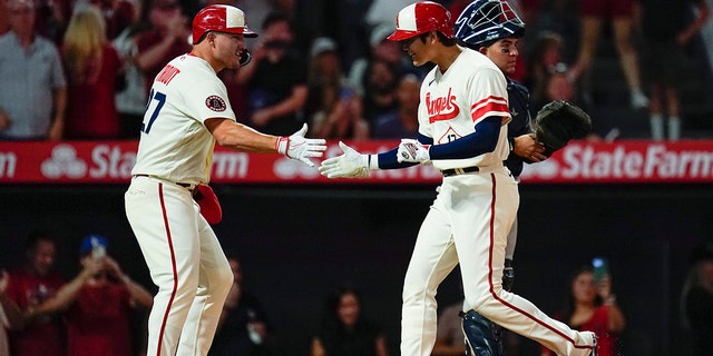 Los Angeles Angels designated hitter Shohei Ohtani, #17, celebrates with Mike Trout, left, after hitting a home run during the sixth inning of a baseball game against the New York Yankees in Anaheim, California, Wednesday, Aug. 31, 2022. David Fletcher and Trout also scored.